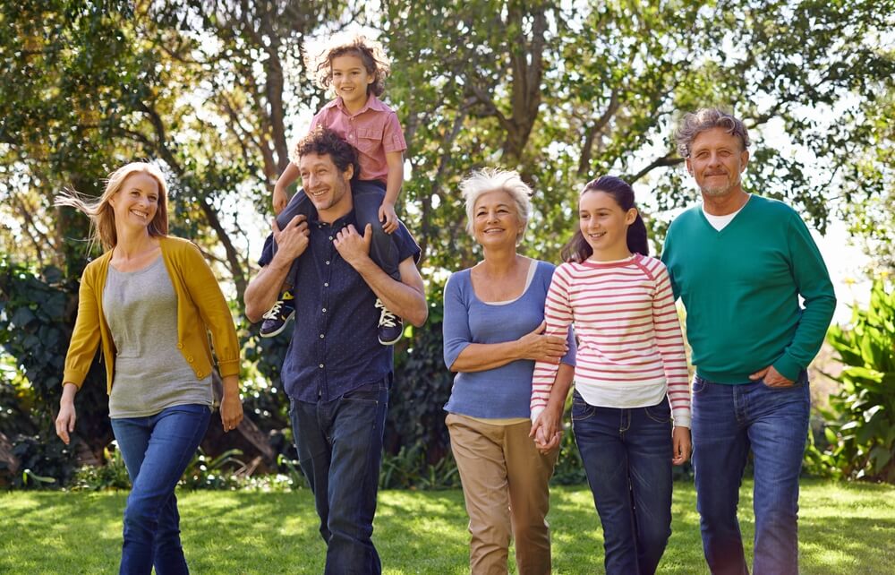 Multi-generational family walks together in park - best life insurance.
