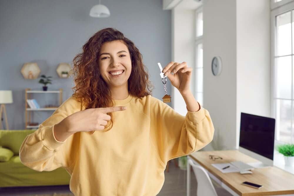 Woman pointing to the keys of her rental house and smiling